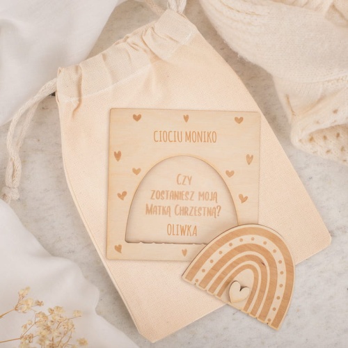 Woreczek z drewnianą tabliczką w postaci tęczy. Pytanie o bycie rodzicem chrzestnym.