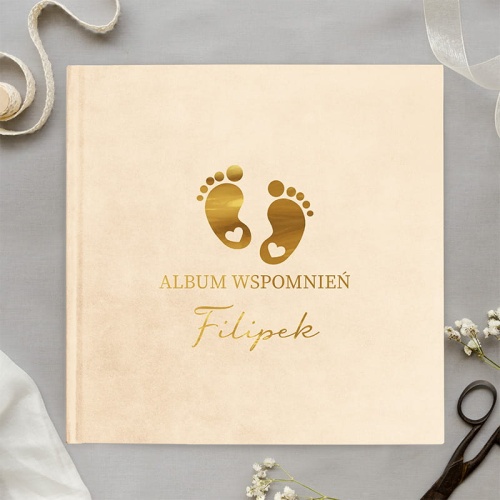 Album z welurową okładką w kolorze kremowym. Na okładce znajduje się grafika przedstawiająca stópki.