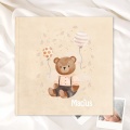 Kremowy album dziecięcy z ilustracją misia i balonami.