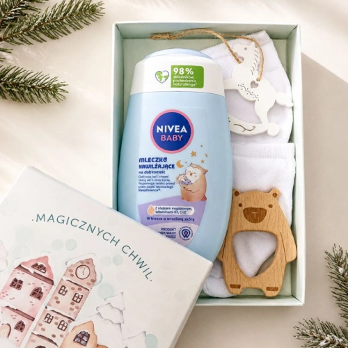 Świąteczny upominek dla niemowlaka zawiera mleczko NIVEA Baby, białe skarpetki, drewniany gryzak i zawieszkę.