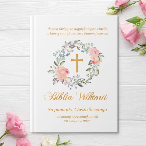 Biblia w białej oprawie z grafika krzyż w wianku oraz personalizacja. Idealnie sprawdzi się jako prezent na Chrzest Święty.