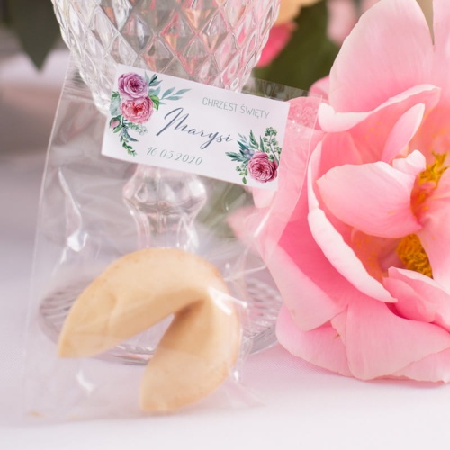 Kruche ciasteczko z wróżbą zapakowane w celofanowe opakowanie, na którym znajduje się biała ozdobna etykieta. Grafika z kolekcji fuksjowy jaskier z personalizacją z imieniem i datą uroczystości.