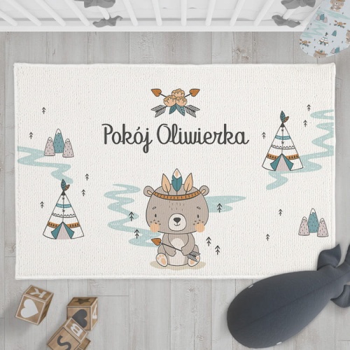Biały dywanik z nadrukiem misia w indiańskim pióropuszu. W tle widać wigwamy i drzewa. Imię dziecka umieszczone na środku dywanika.