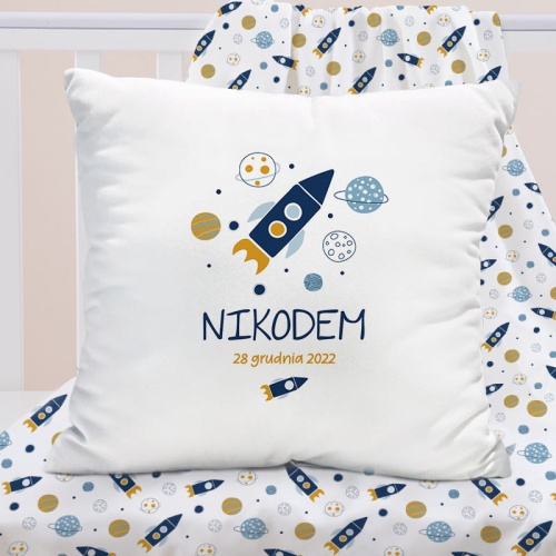Biała kwadratowa poduszka. Dekoracja do pokoju dziecka z grafiką granatowej planety oraz planet. Imię dziecka i data urodzenia umieszczona pod rakietą.