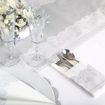 Element dekoracyjny, białe kieszonki na sztućce ze srebrną koronką. Elegancka dekoracja stołu.